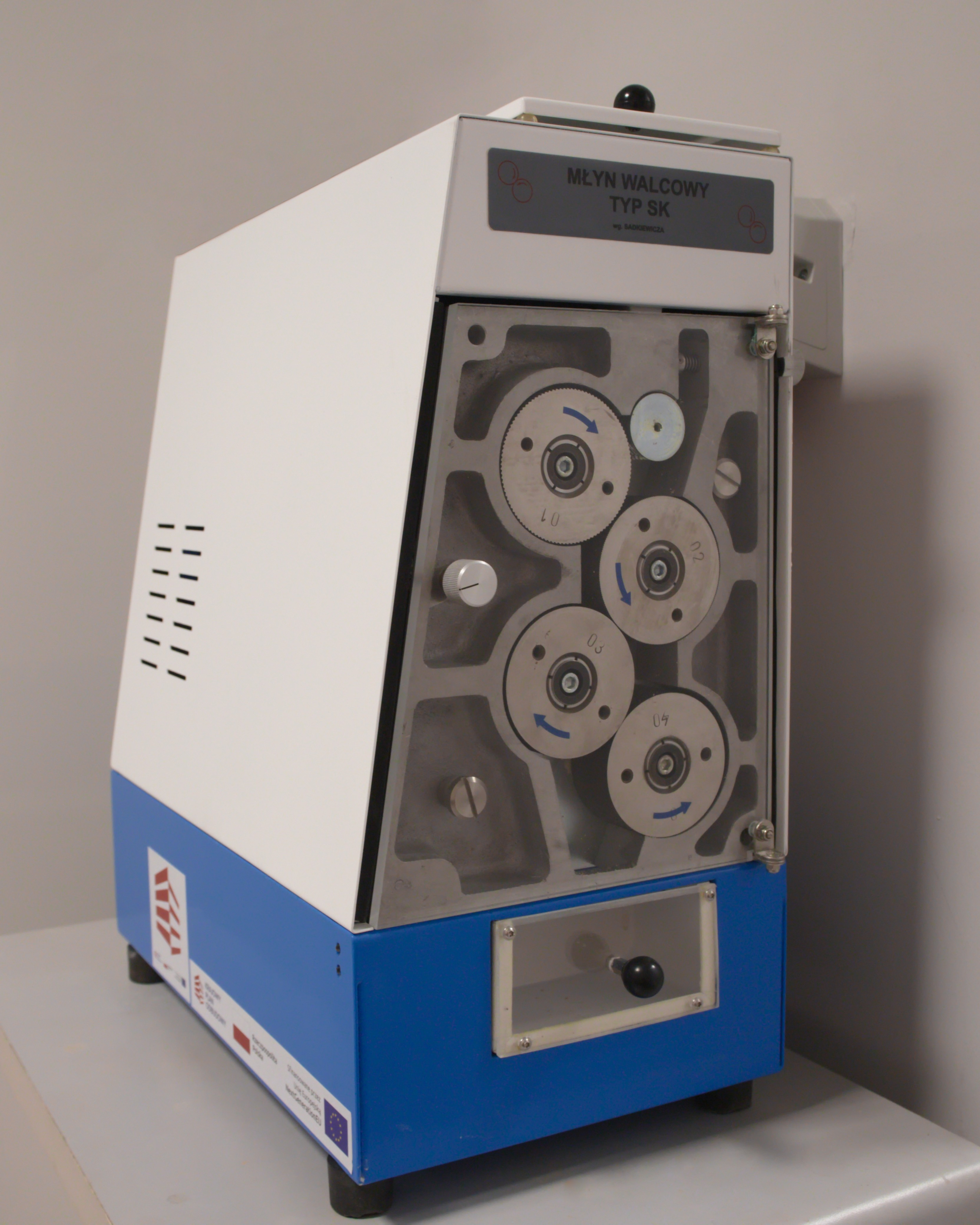 Laboratoryjny młynek czterowalcowy do przemiału ziarna z widocznym mechanizmem walców za przeźroczystą osłoną